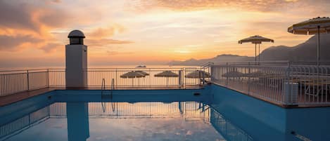 Una piscina al aire libre de temporada, sombrillas