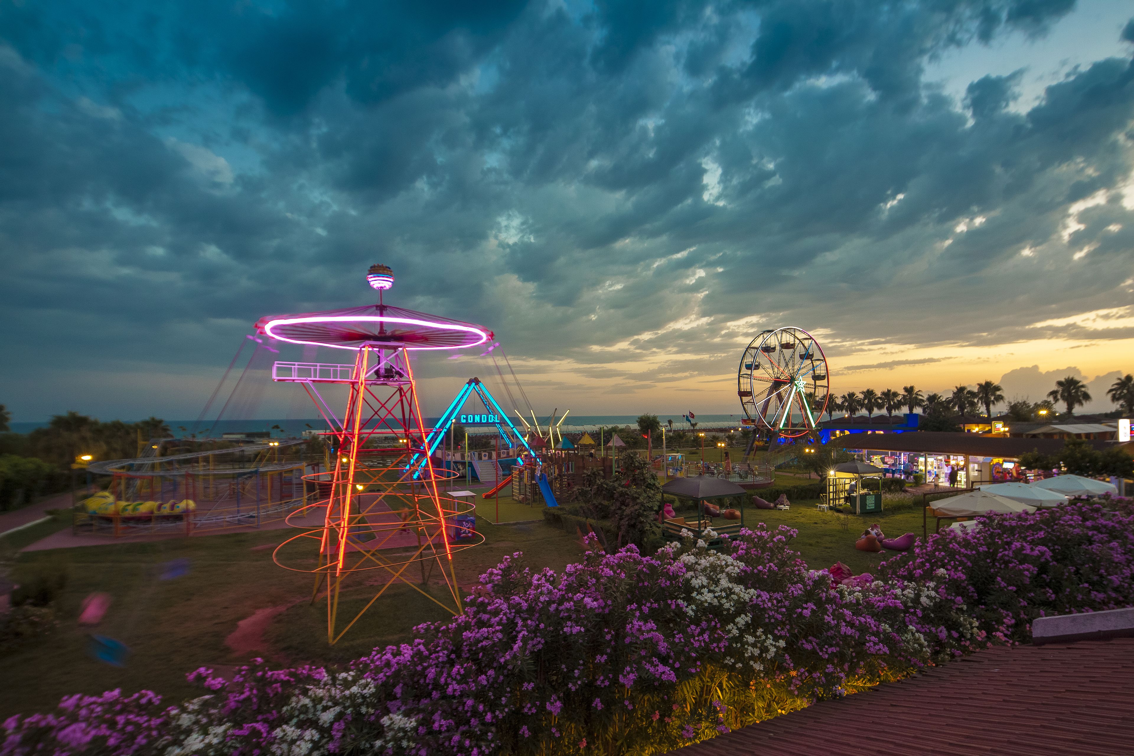A Ferris wheel and a swing ride at an amusement park during dusk.