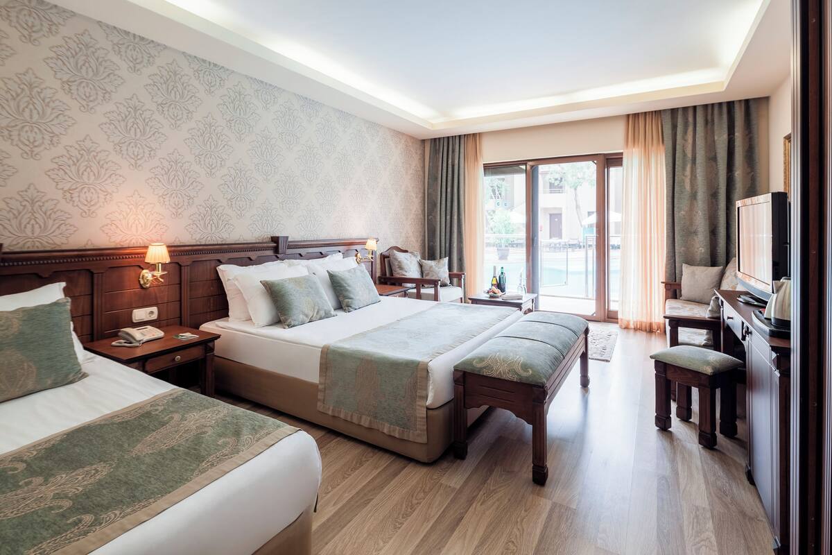 Ein Hotelzimmer mit einem großen Bett, einem Schreibtisch, einem Stuhl und einem Fernseher.
