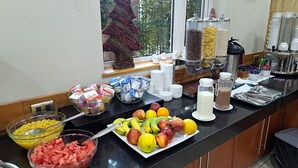 Ein Frühstücksbuffet mit verschiedenen Speisen, darunter Obst, Müsli und Getränke.