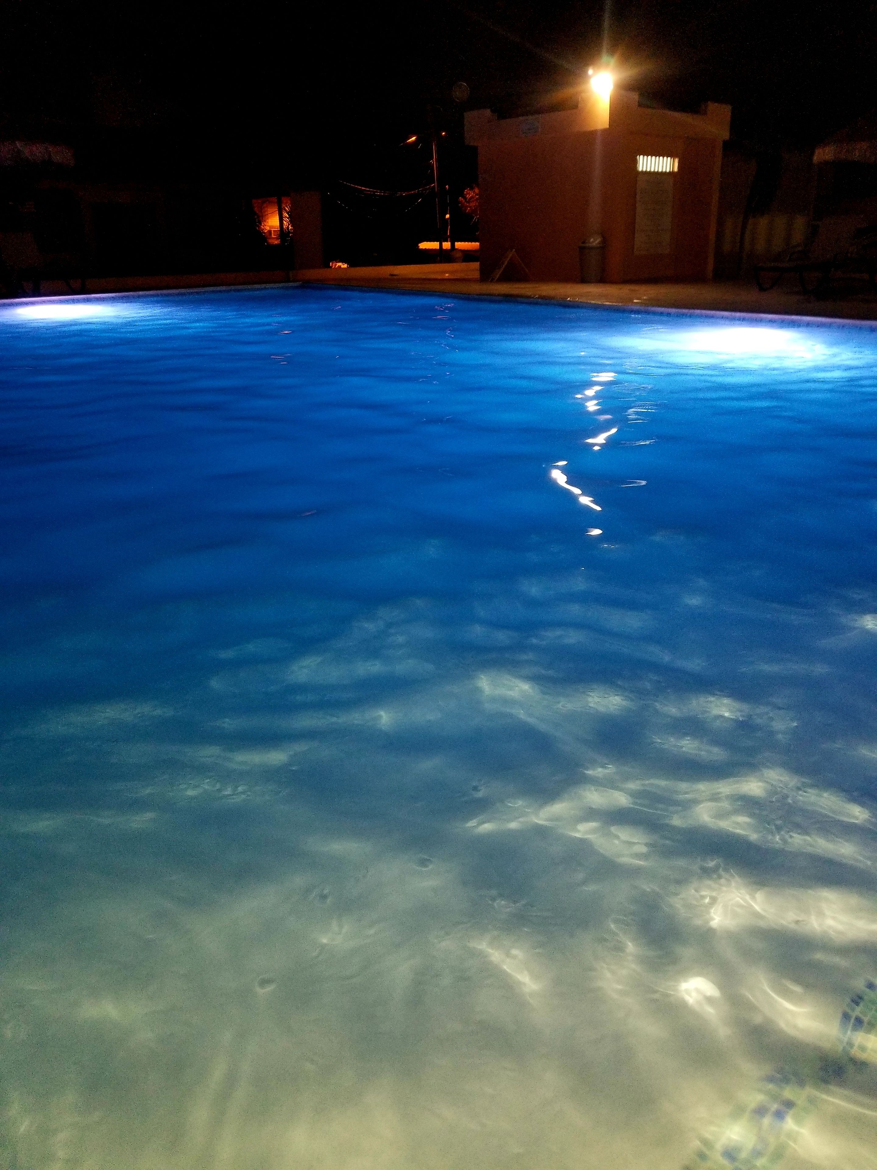 Ein Schwimmbecken mit klarem Wasser und einem Gebäude im Hintergrund.