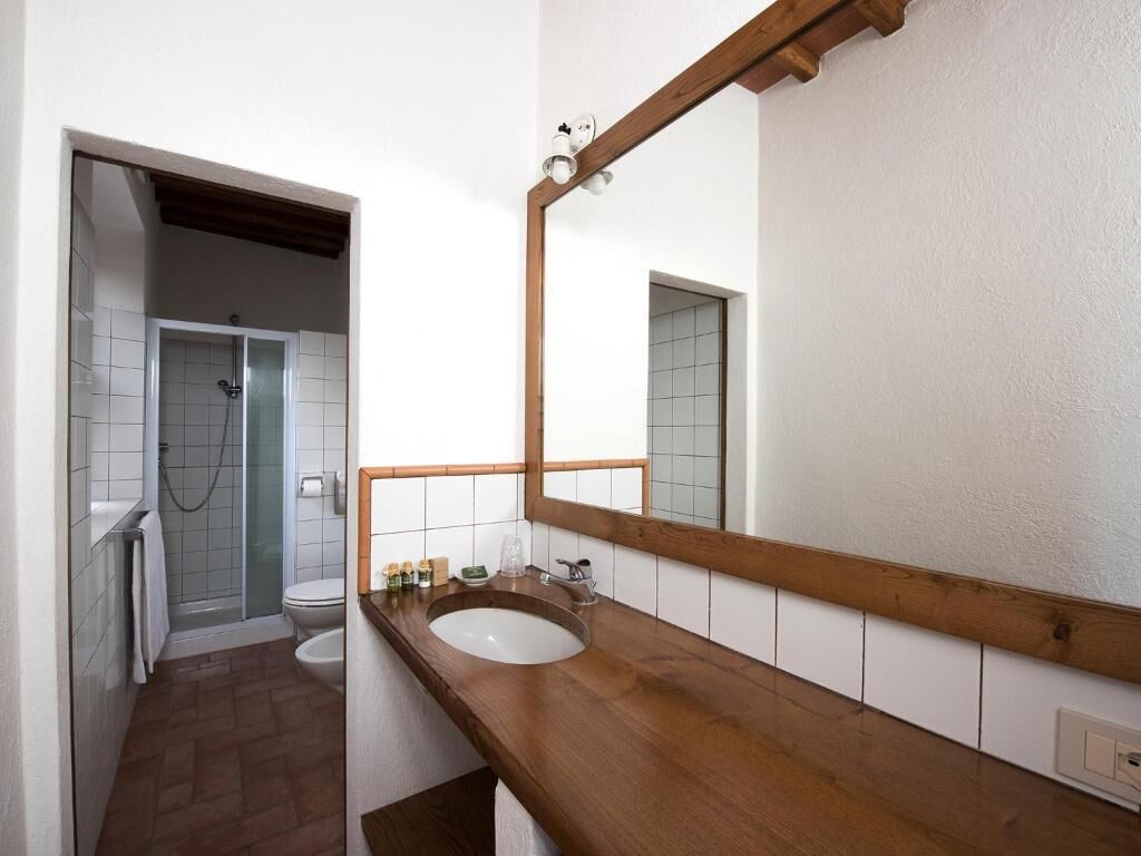 A bathroom with a wooden vanity, a large mirror, a shower, and a toilet.