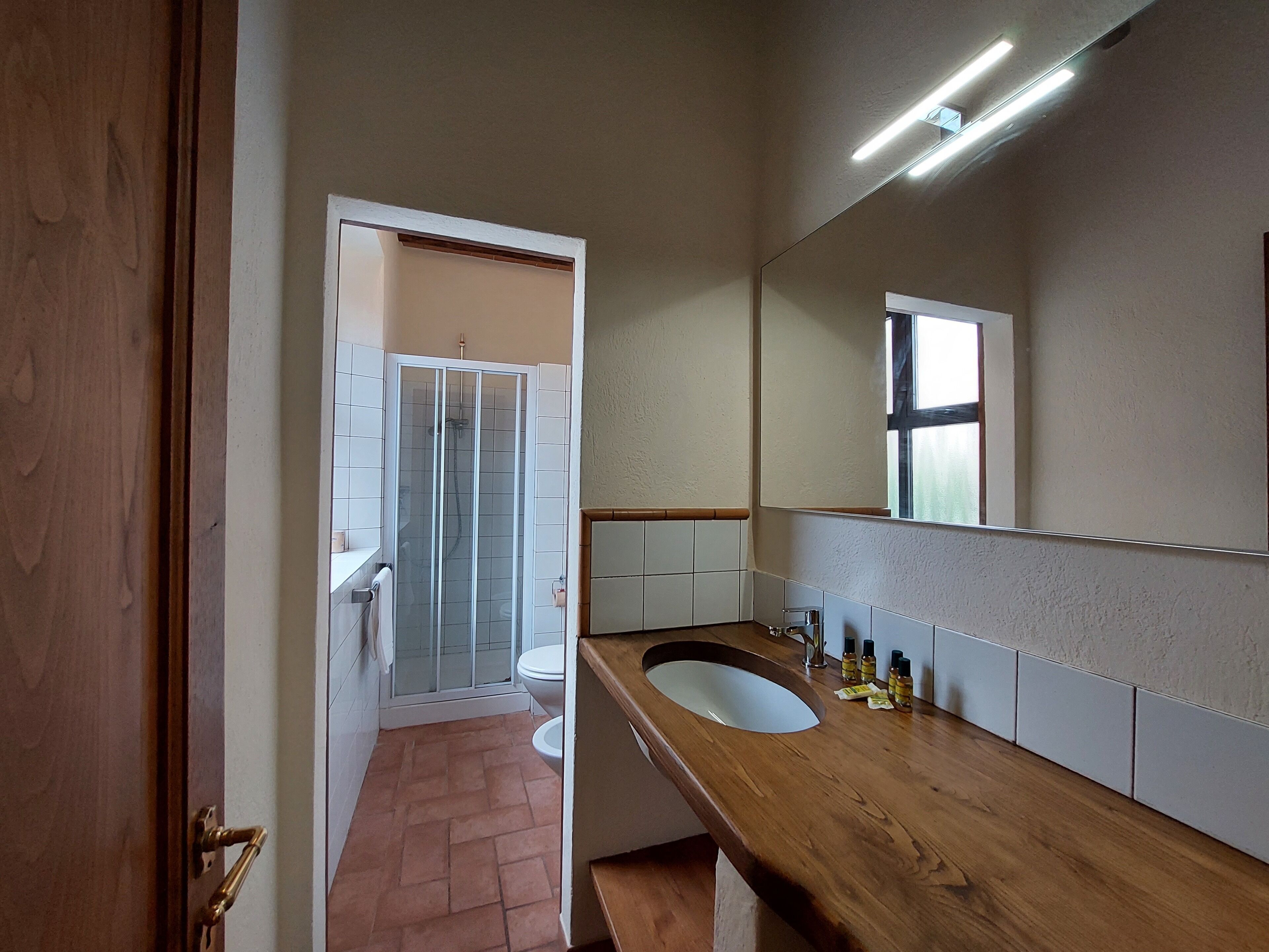 A bathroom with a wooden vanity, a glass shower enclosure, and a large mirror.