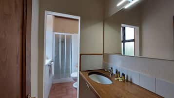 A bathroom with a wooden vanity, a glass shower enclosure, and a large mirror.