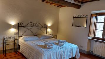 Une chambre à coucher comprenant un lit, deux tables de chevet, une commode, une fenêtre et un miroir fixé au mur.