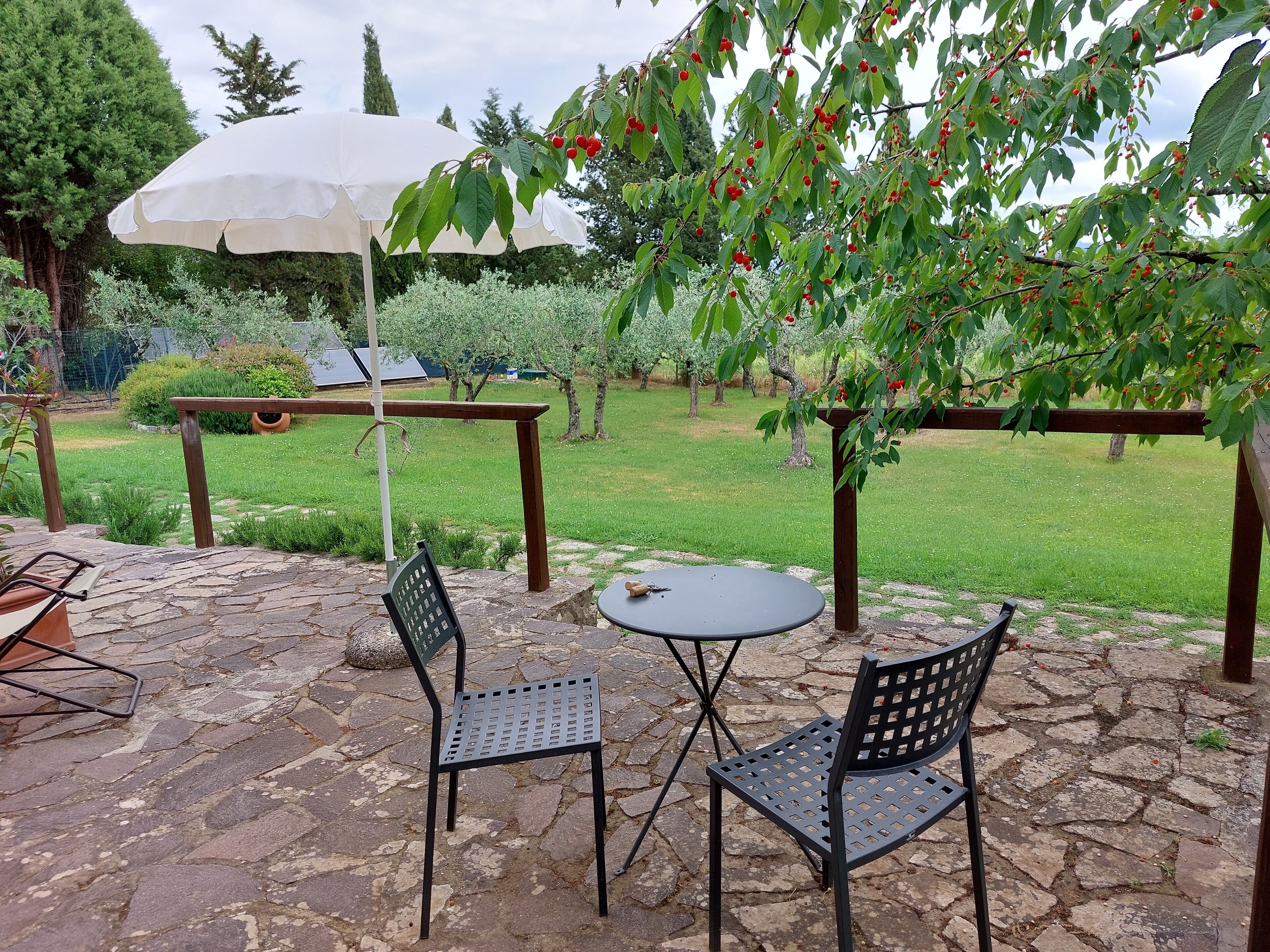 An outdoor patio with stone flooring, two metal chairs, a small round table, and a white umbrella.