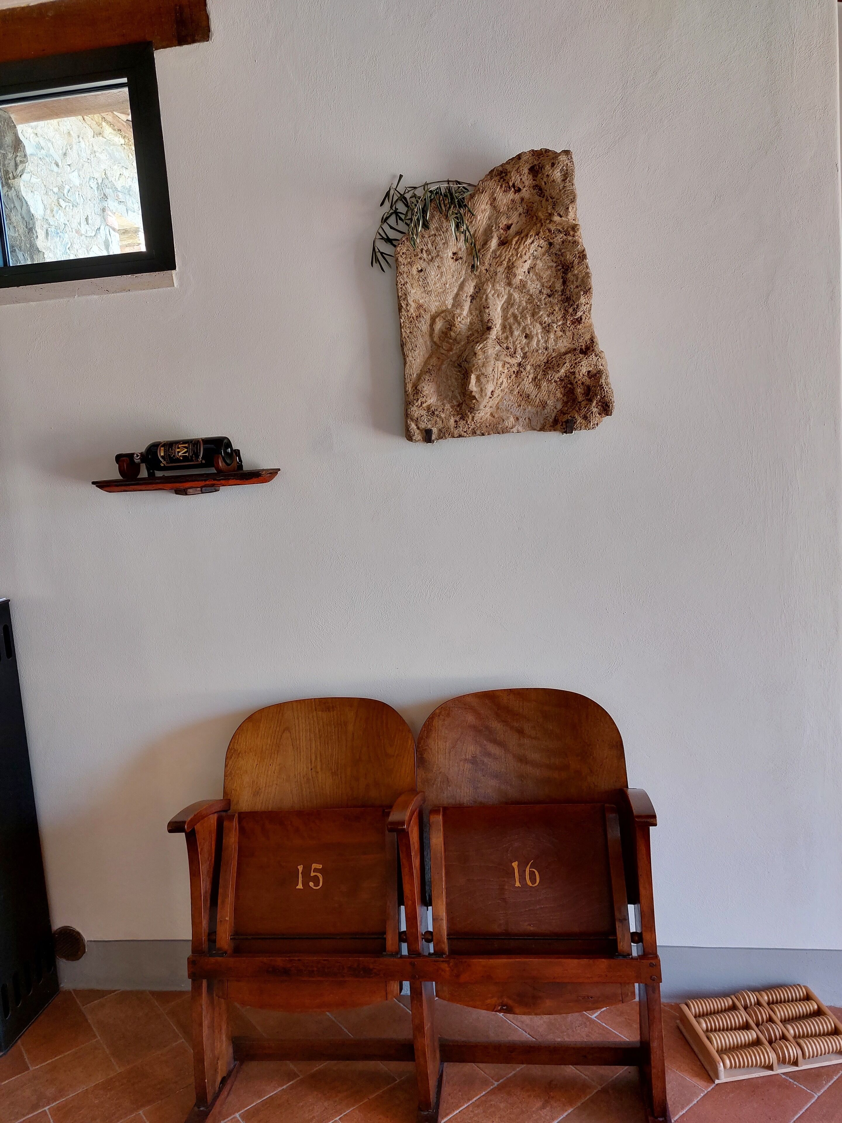 Une pièce avec un banc en bois portant les numéros 15 et 16, un tapis en fourrure et une petite étagère sur laquelle se trouvent une bouteille et une voiture jouet.