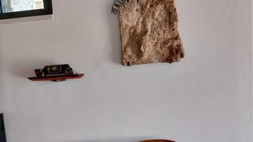 Une pièce avec un banc en bois portant les numéros 15 et 16, un tapis en fourrure et une petite étagère sur laquelle se trouvent une bouteille et une voiture jouet.