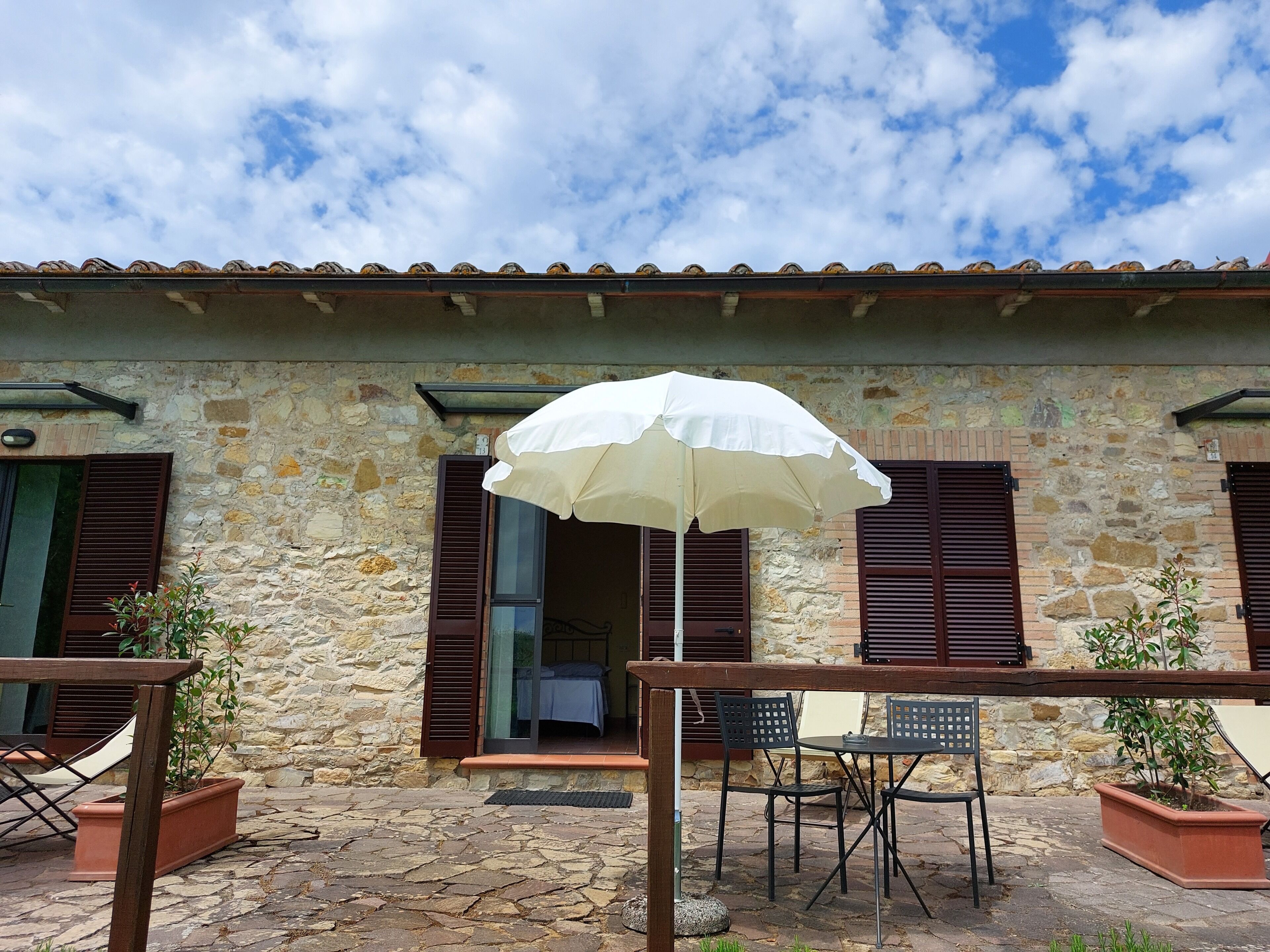 A stone building with a tiled roof, a white umbrella, and outdoor furniture.