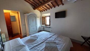 Een slaapkamer met een bed, een dressoir, een spiegel en een televisie.