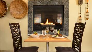 Un comedor con una mesa dispuesta para dos, una chimenea y decoración en la pared.