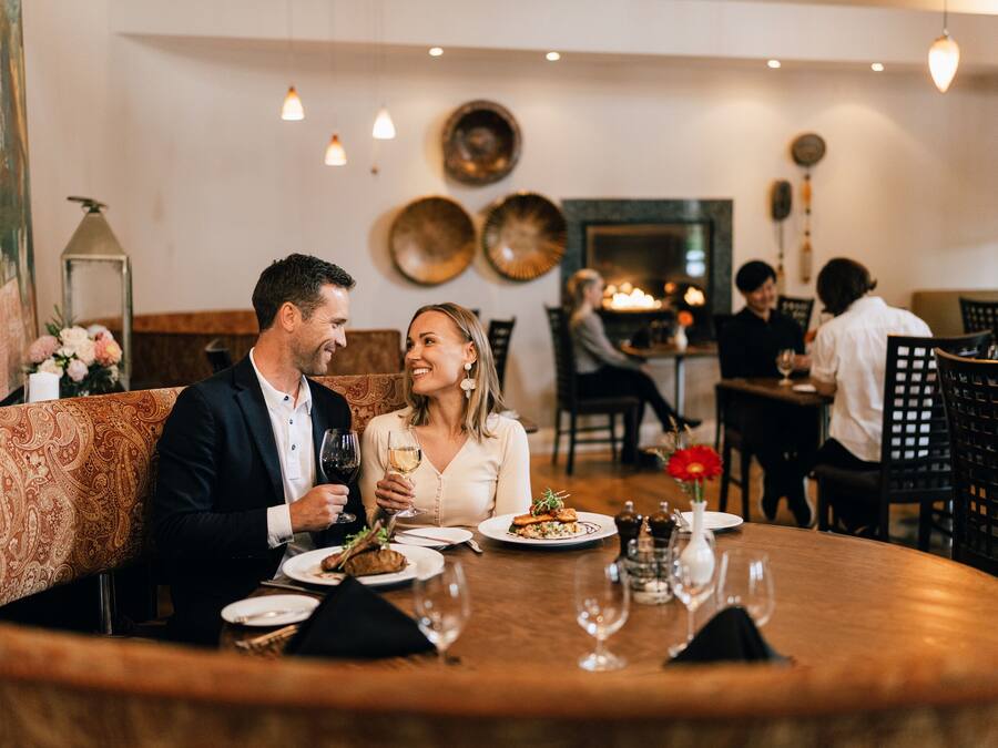 A couple dining at a restaurant with a round table, candles, and a warm ambiance.