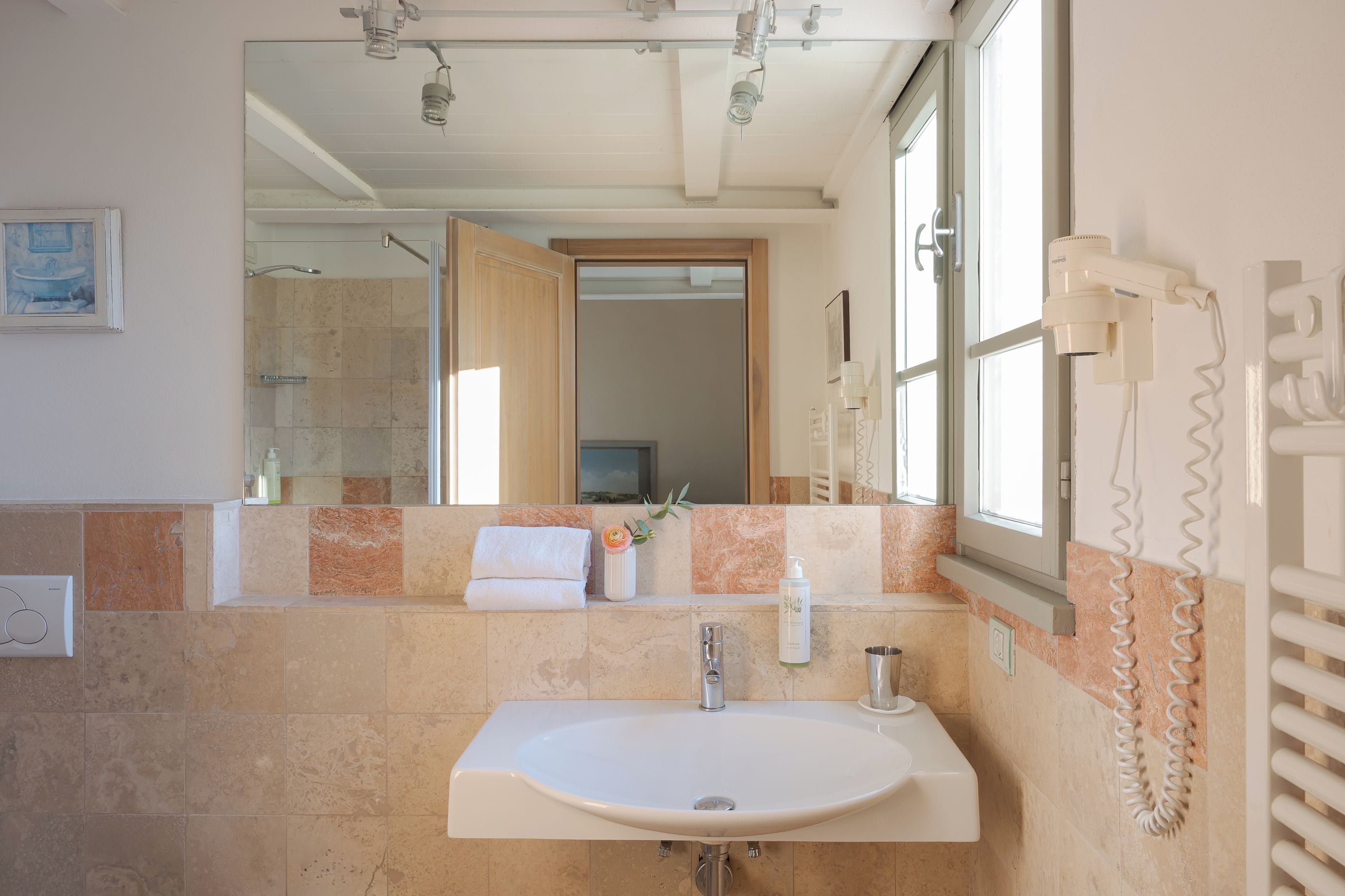 A bathroom with a large mirror, a sink, and a towel rack.
