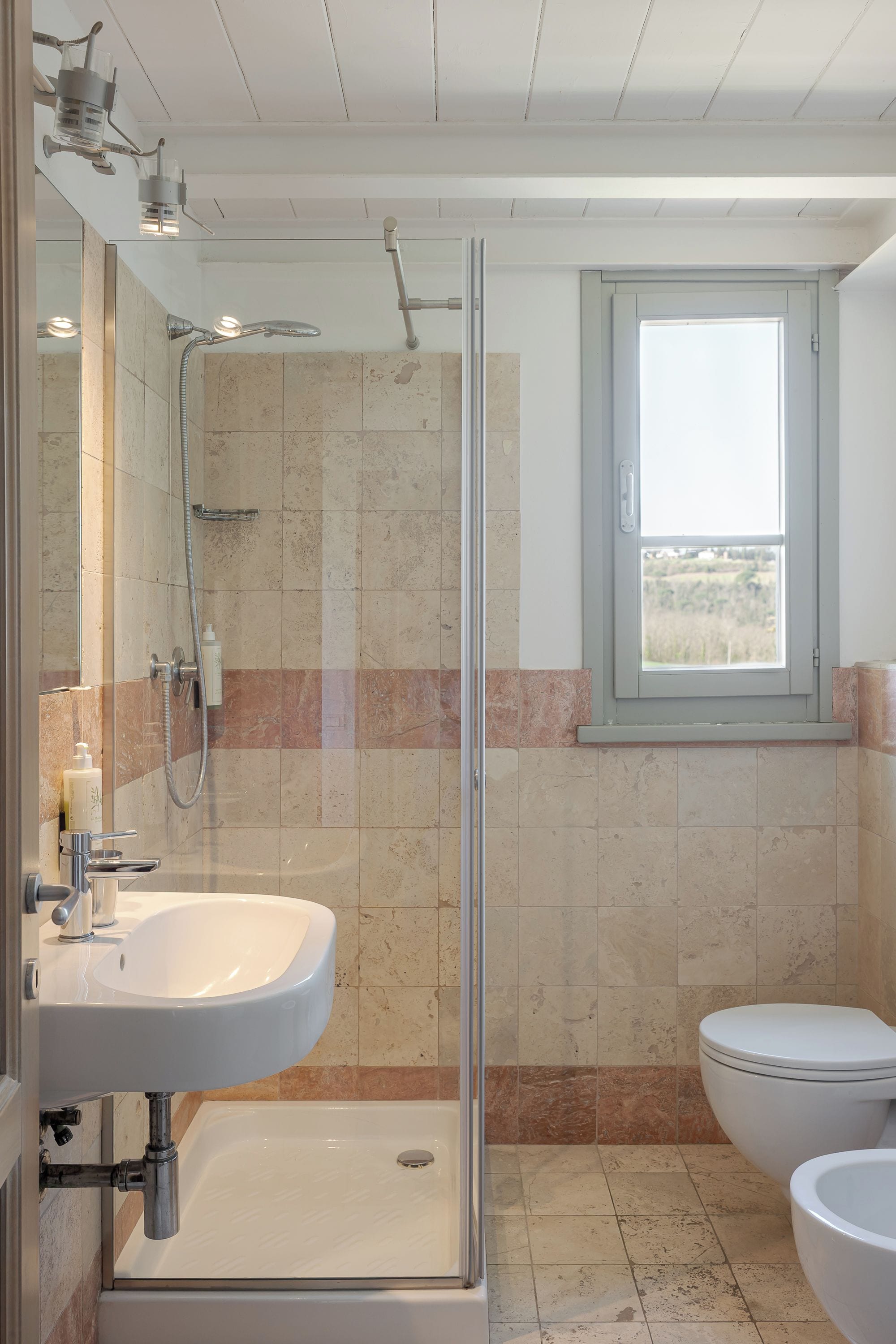 Un baño con ducha de vidrio, lavamanos e inodoro.