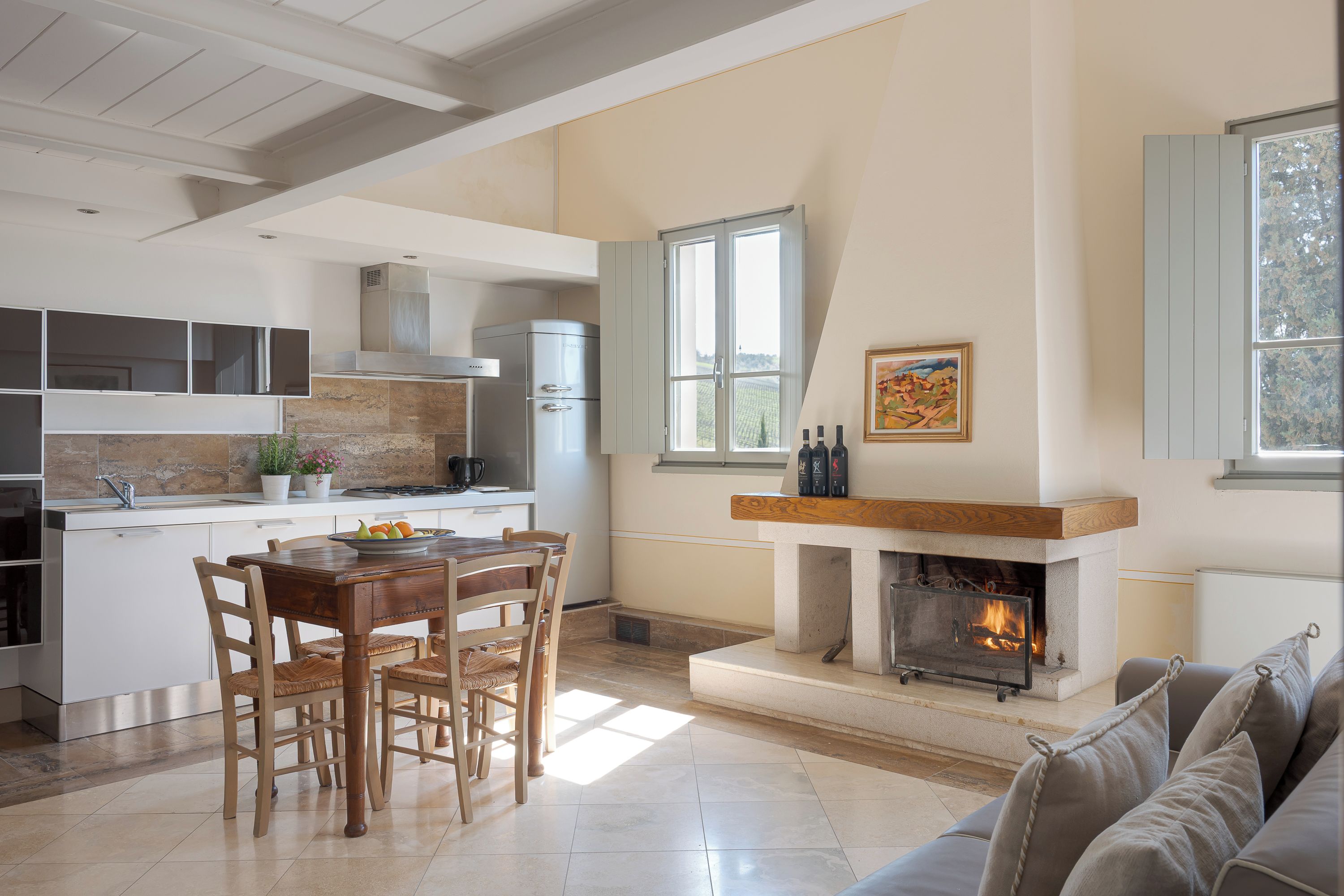 A spacious living area with a fireplace, a dining table with chairs, and a kitchen area with modern appliances.