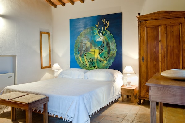 Une chambre à coucher avec un lit, des tables de chevet, une armoire en bois et un grand tableau accroché au mur.