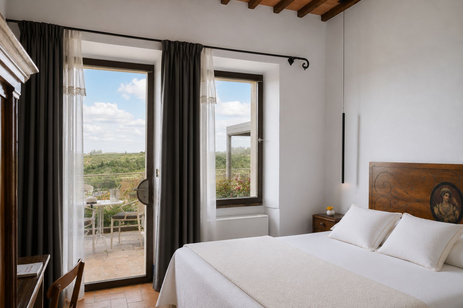 A hotel room with a bed, a small table, a chair, and a view of the outdoors through a sliding door.