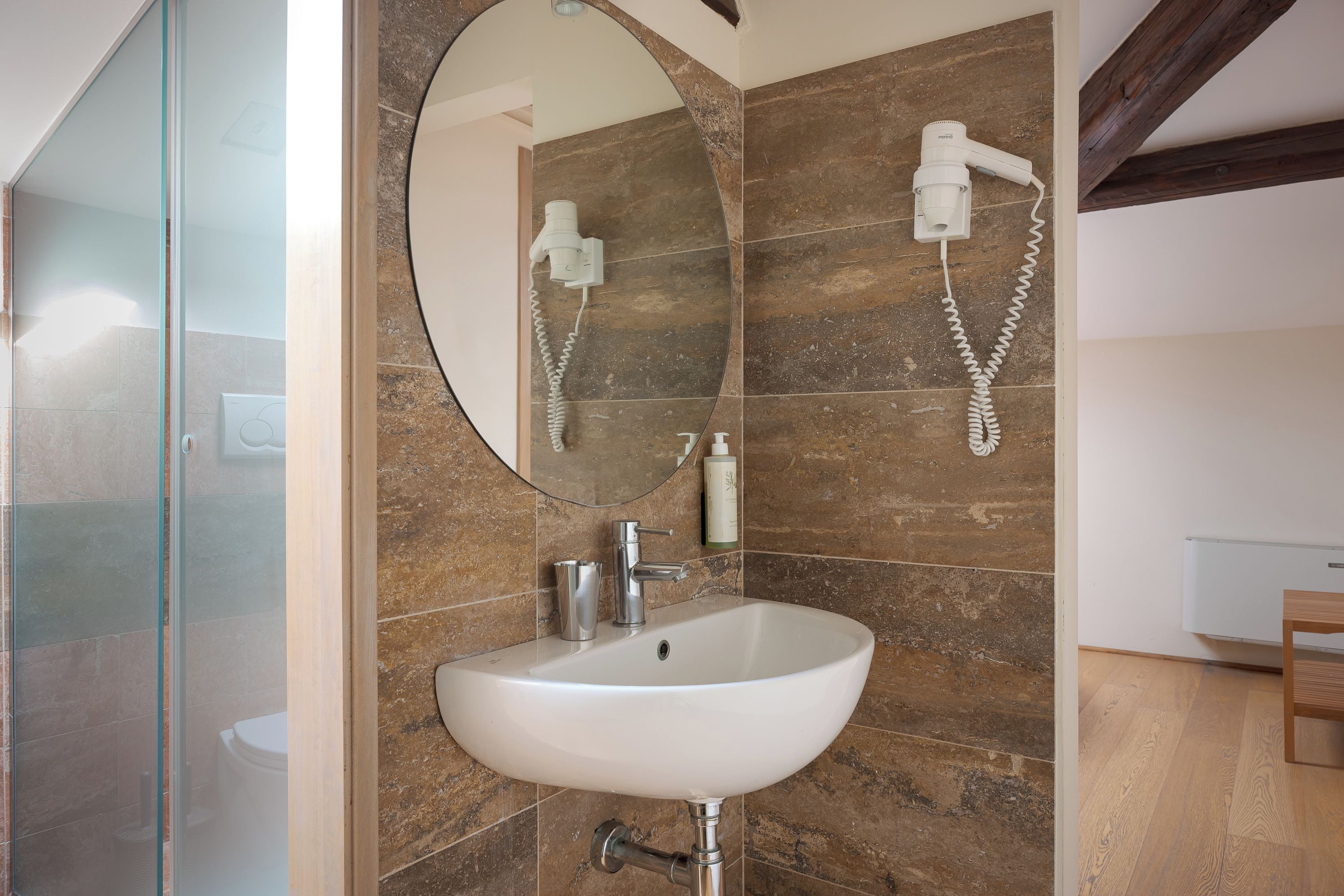 A bathroom with a white sink, a glass shower enclosure, and a mirror.