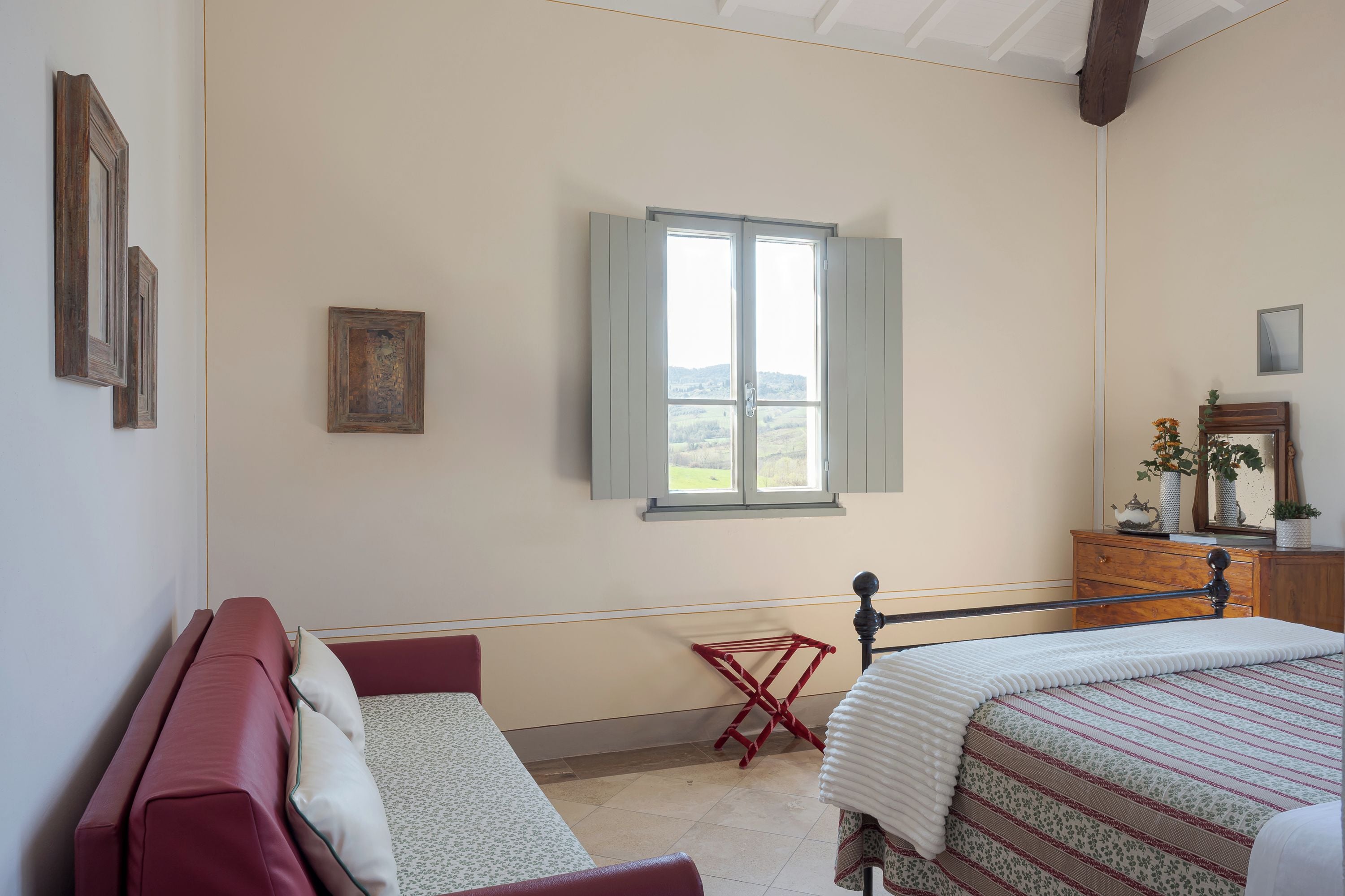 Une chambre à coucher avec un lit, un banc, une fenêtre et une commode.