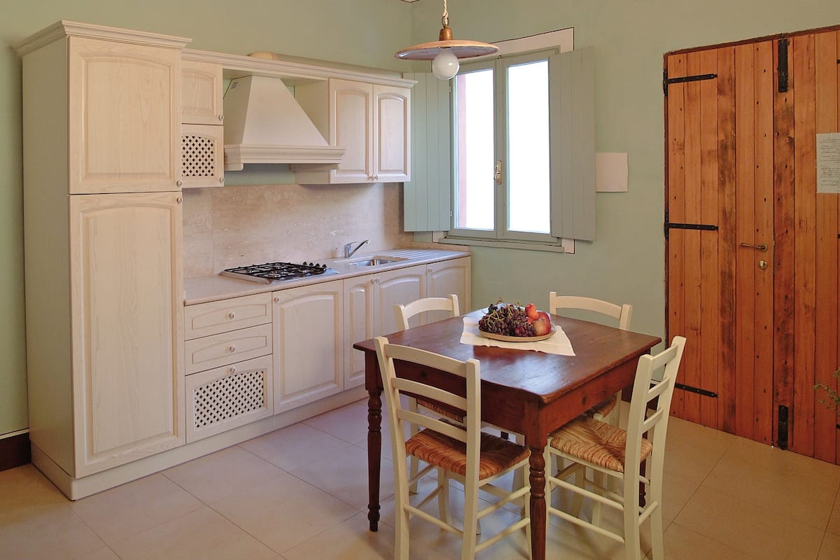 A kitchen with white cabinets, a wooden dining table, and a wooden door.
