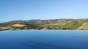 A pool with a view of rolling hills and distant buildings. - Poderi Arcangelo (San Gimignano)