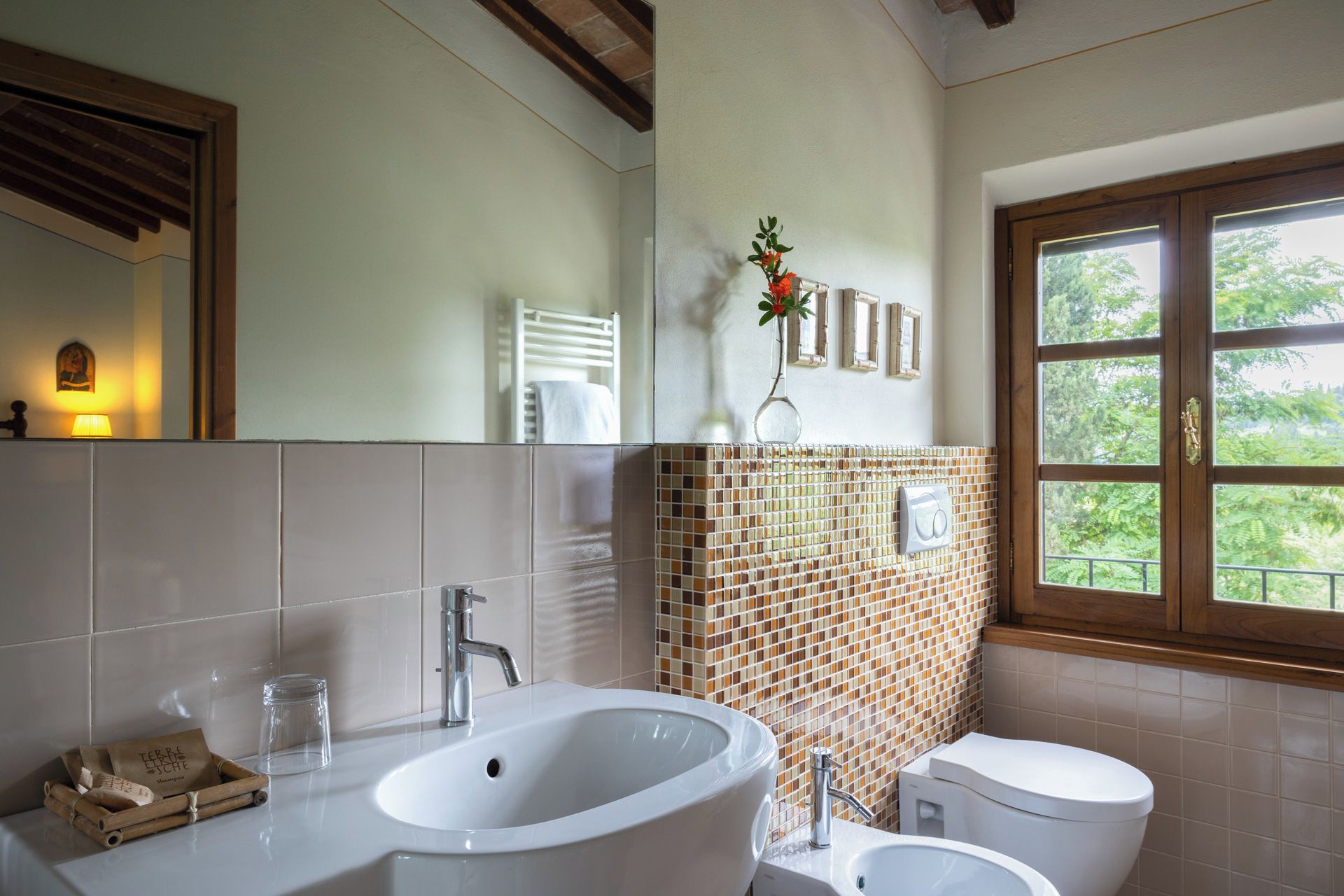 A bathroom with a large bathtub, a toilet, and a sink. There is a window with a view of greenery outside.