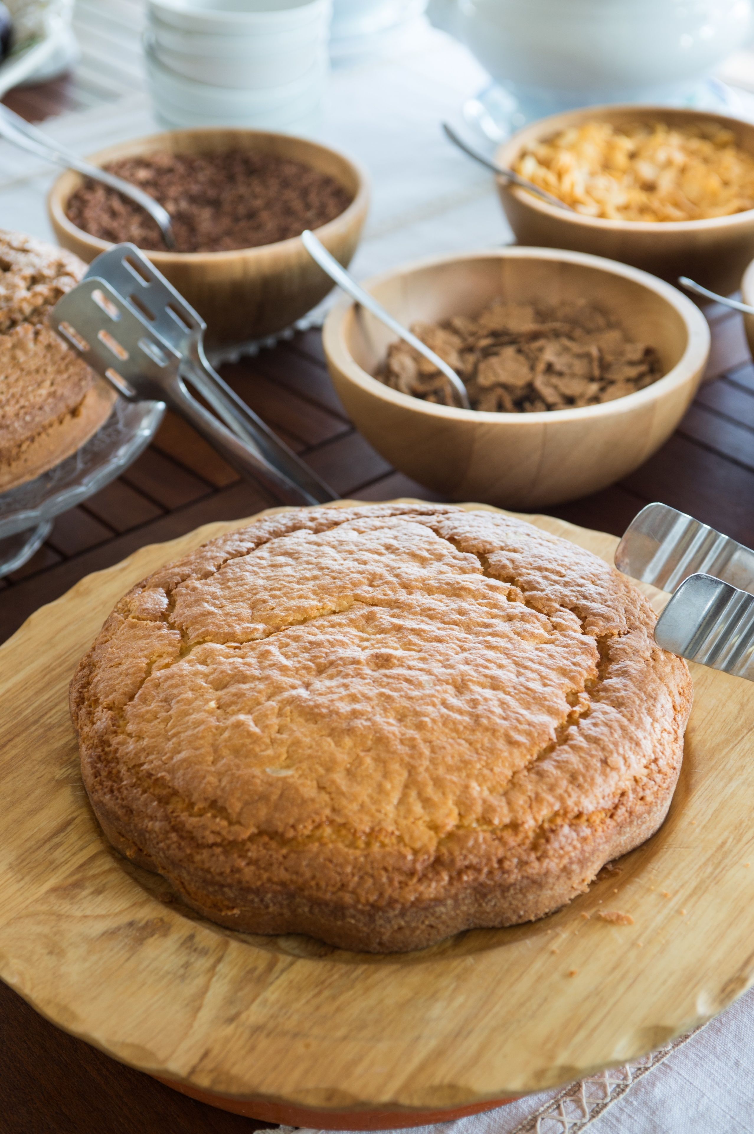 A round cake on a wooden board with a fork beside it.