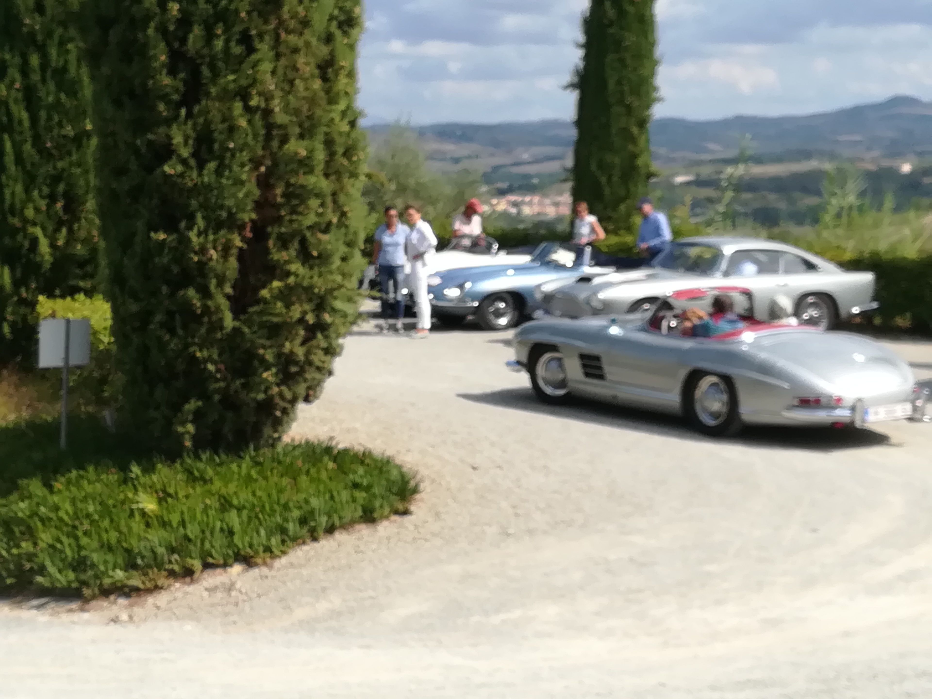A gravel road with vintage cars parked on the side.