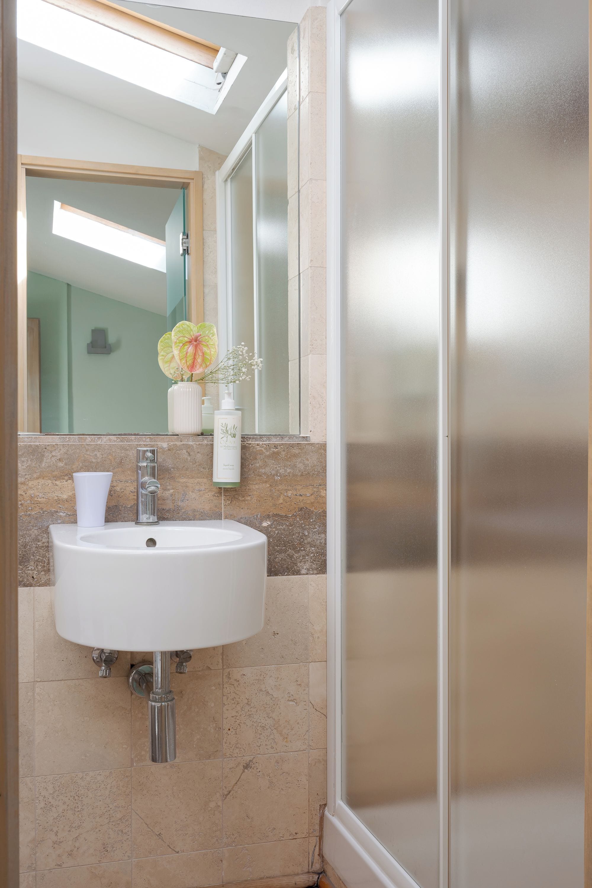 A bathroom with a white sink, a mirror, and a shower area.