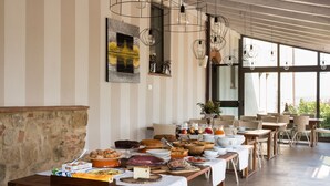 A buffet setup with various food items and a seating area with wicker chairs and tables. - Poderi Arcangelo (San Gimignano)