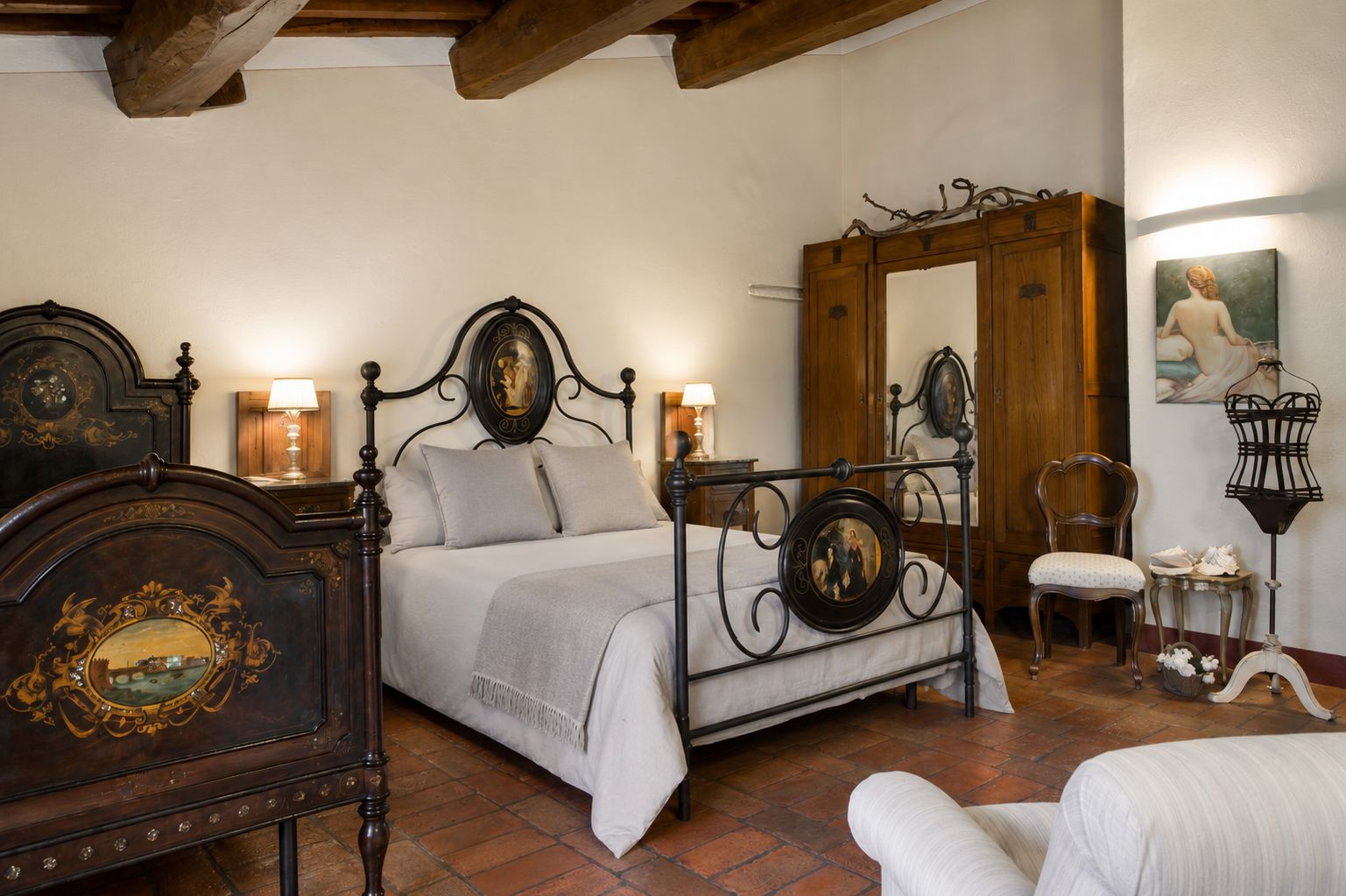 Una camera da letto tradizionale con un letto a baldacchino, un armadio in legno, una sedia e uno specchio.