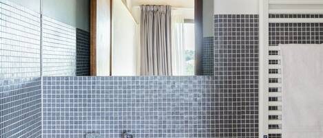 A bathroom with a white sink, a mirror, a towel rack, and a window with curtains.
