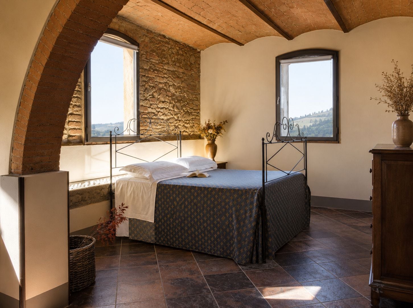 Quarto com uma cama, duas janelas, uma parede de pedra e vista para o campo.