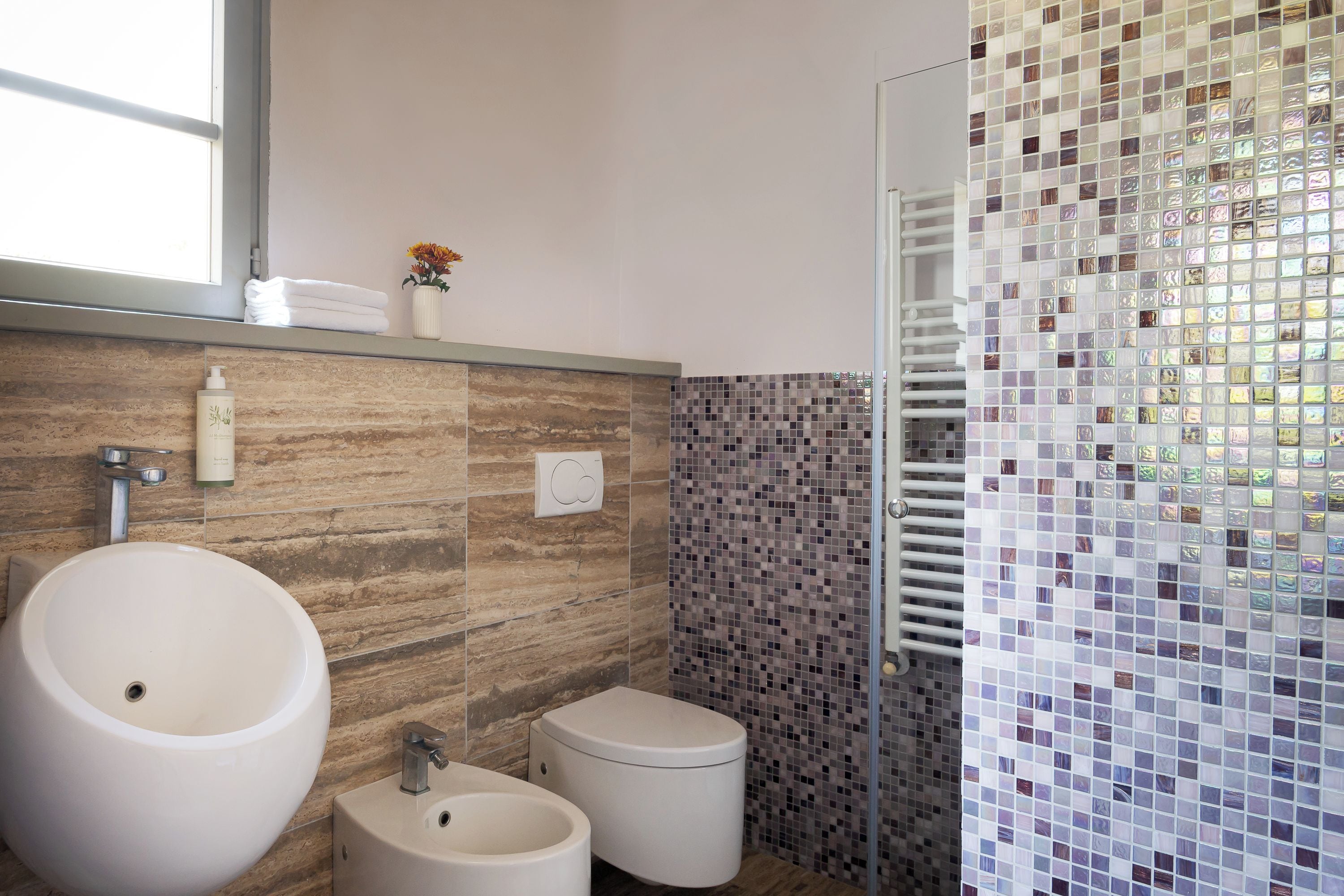 Un baño con un lavamanos grande, un bidé, un inodoro y una zona de ducha con puerta de cristal.