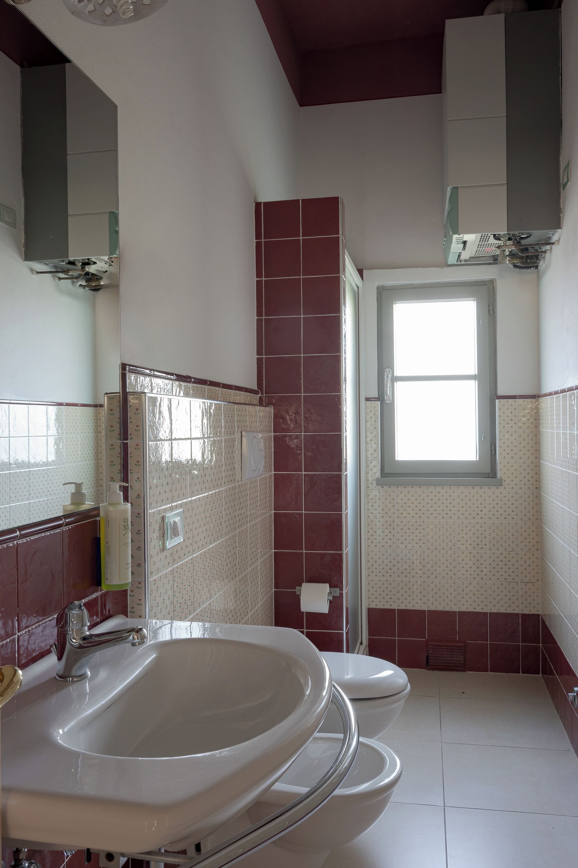A bathroom with a bathtub, toilet, and a window.