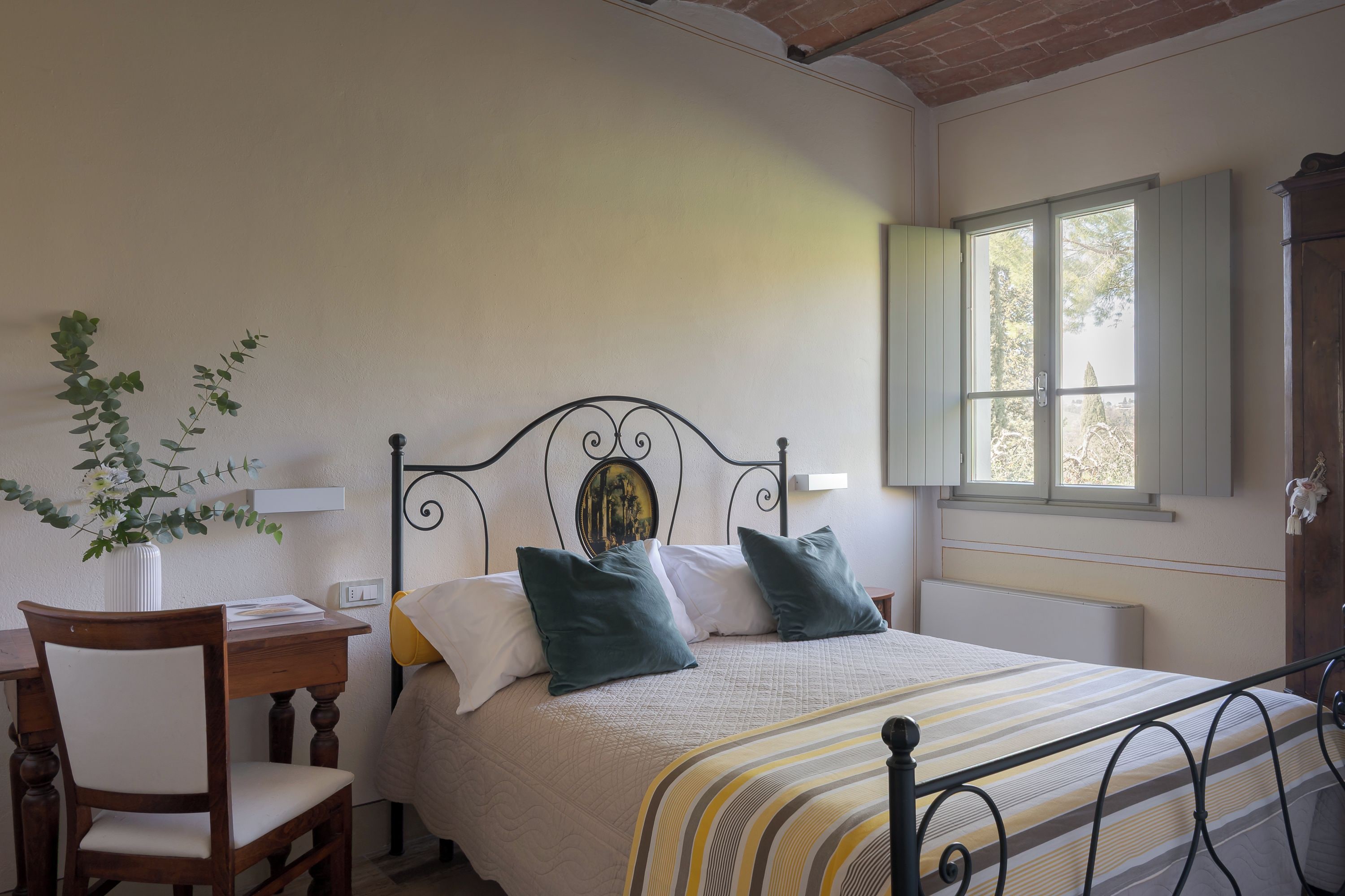 Un dormitorio con cama, una silla, un escritorio y una ventana.