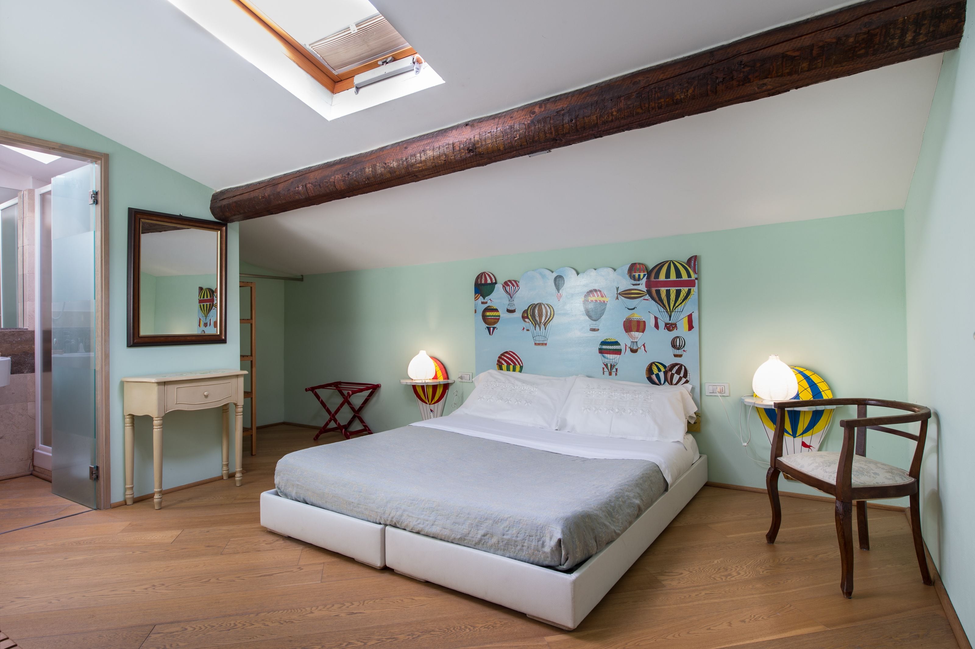 Een slaapkamer met een bed, bedlampen, een stoel, een bureau en een spiegel.