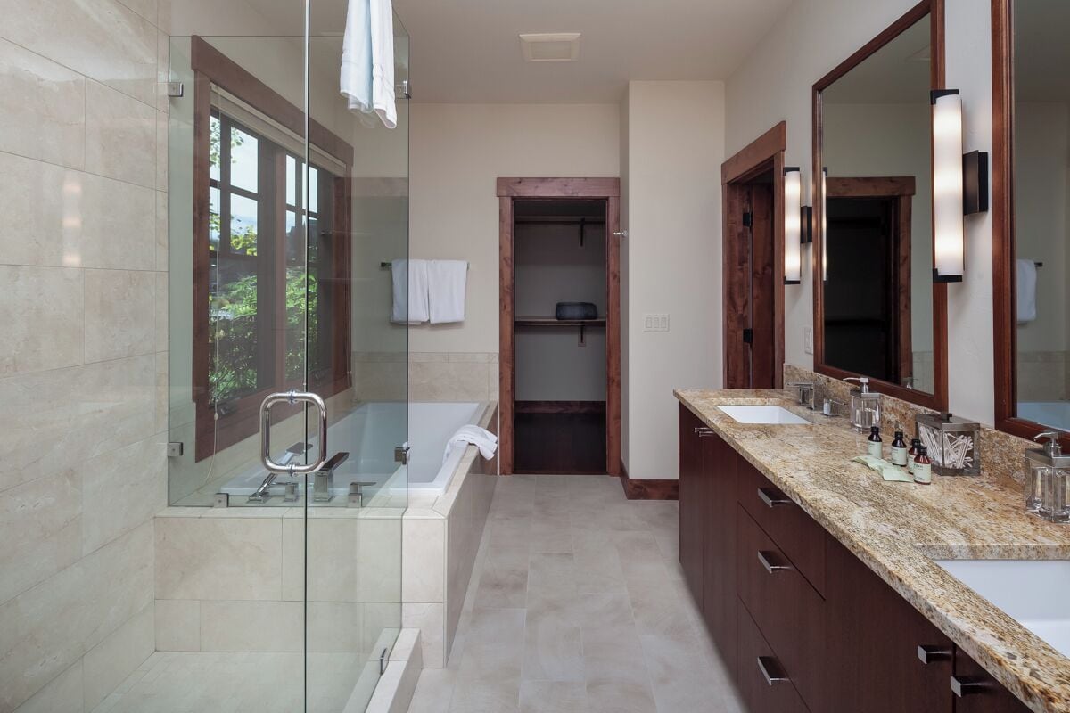 A modern bathroom with a glass-enclosed shower, a double sink vanity, and a large mirror.