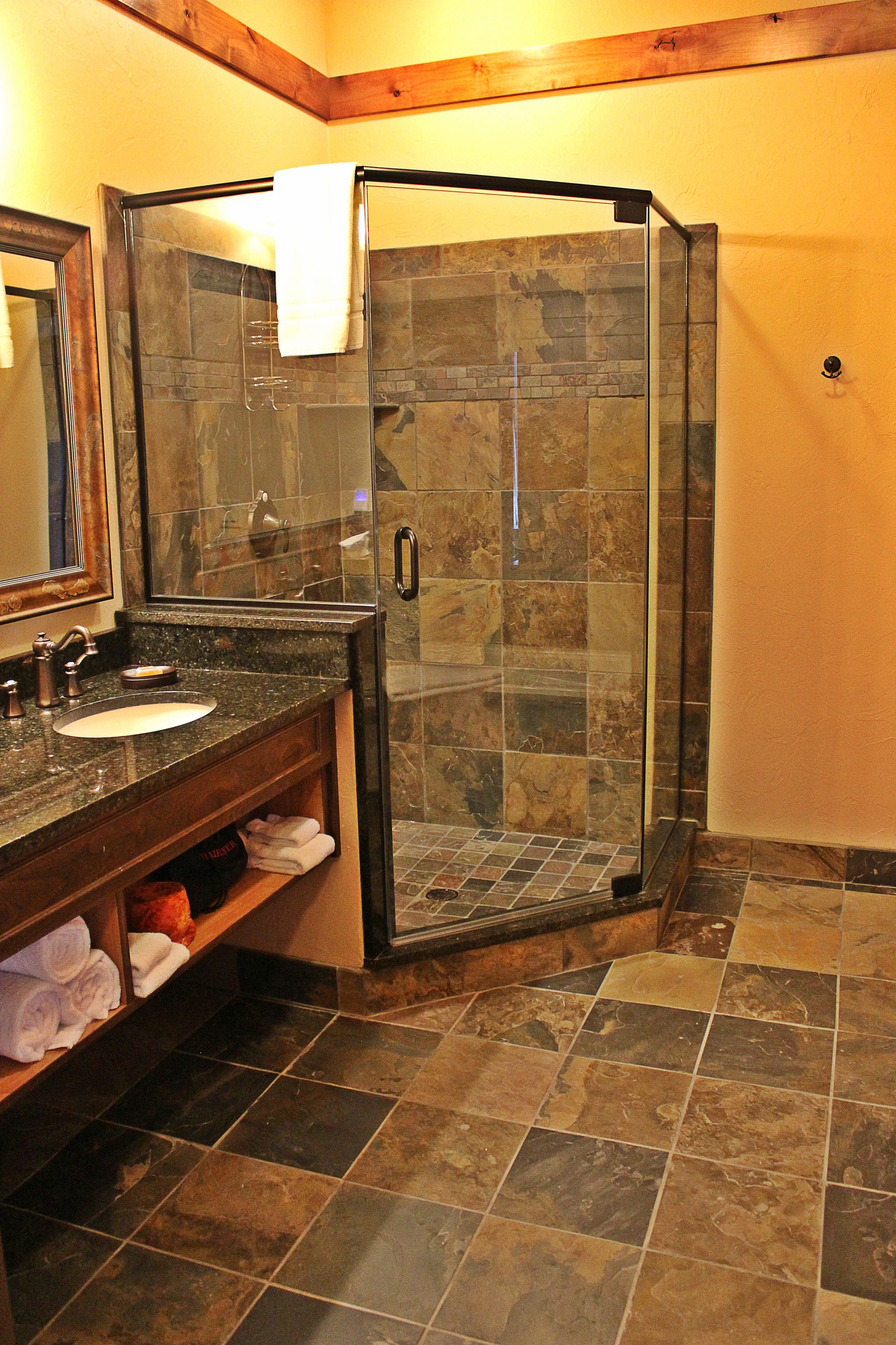 Un baño con cabina de ducha de vidrio, un lavabo con encimera de mármol y un espejo sobre el lavabo.