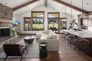 A spacious living area with a fireplace, a large sofa, and a kitchen with a bar.