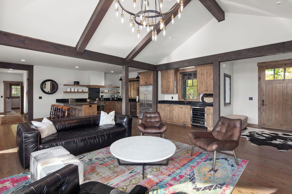 A spacious living room with a leather sofa, a round coffee table, and a chandelier.