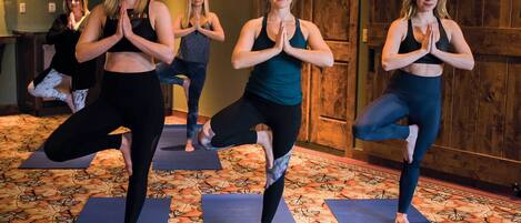 Ein Yoga-Kurs in einem Raum mit gemustertem Teppich und Holzwänden.