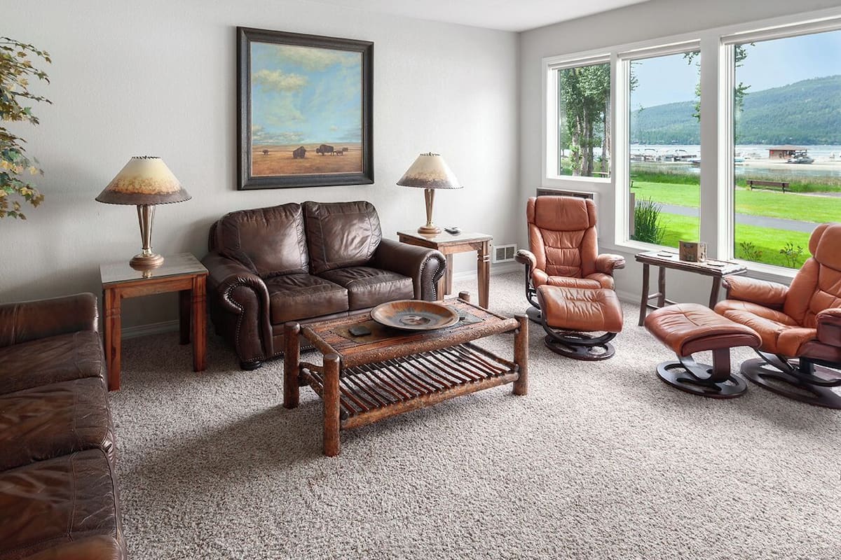 A living room with leather furniture, a coffee table, and two floor lamps.