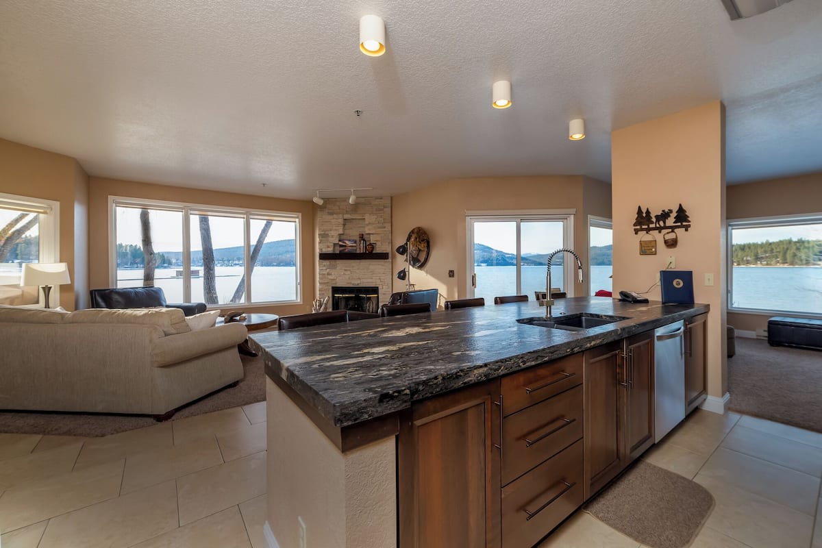 A spacious kitchen with a large island, a dining area, and a view of a lake.