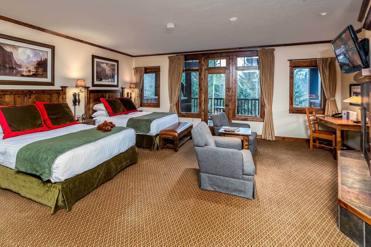 A hotel room with two beds, a sofa, a desk, and a TV.
