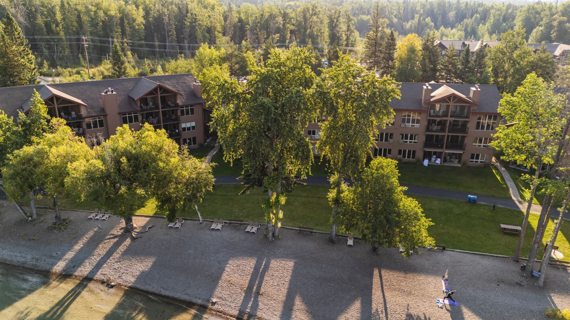 A multi-story hotel with a central courtyard, surrounded by trees and a parking area.