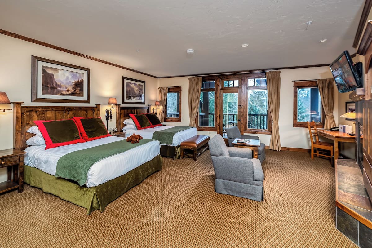 A hotel room with two beds, a sofa, a TV, and large windows.