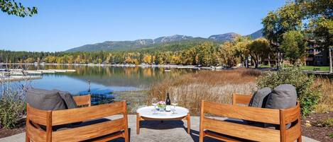 A wooden bench and table set by a lake with a mountain backdrop.