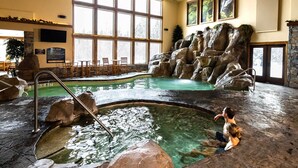 An indoor pool with rock formations and a seating area. - Lodge at Whitefish Lake (Whitefish)