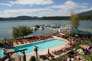 A resort with a swimming pool, lounge chairs, and a dock with boats.